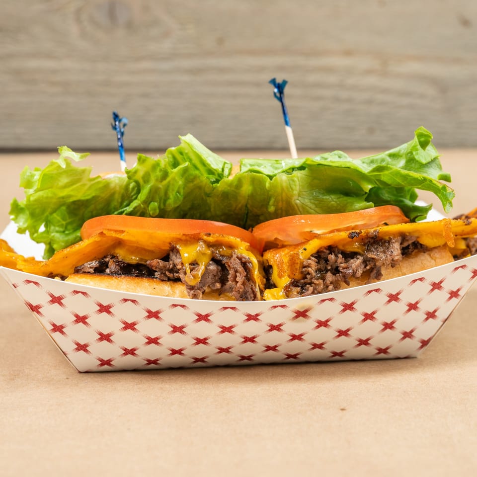 Two Squeeze Burgers with melted cheese, tomatoes, and lettuce in a paper tray.